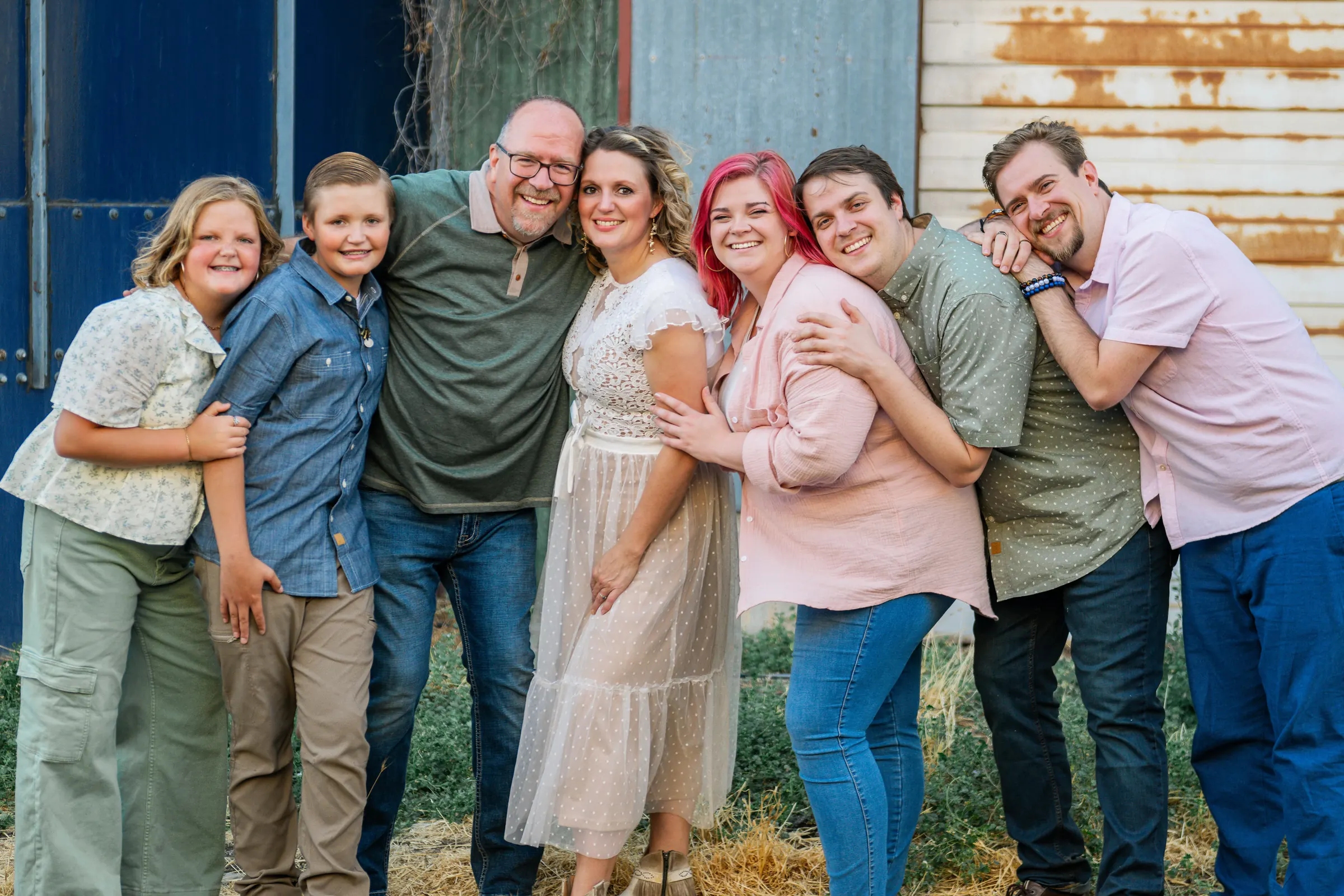 The family in a group hug by the barn